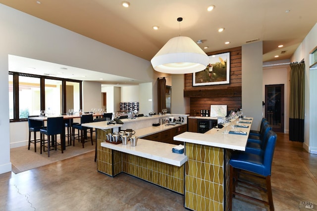 kitchen with a breakfast bar, finished concrete flooring, recessed lighting, visible vents, and light countertops