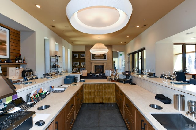 kitchen featuring recessed lighting, a multi sided fireplace, open floor plan, light stone countertops, and brown cabinetry