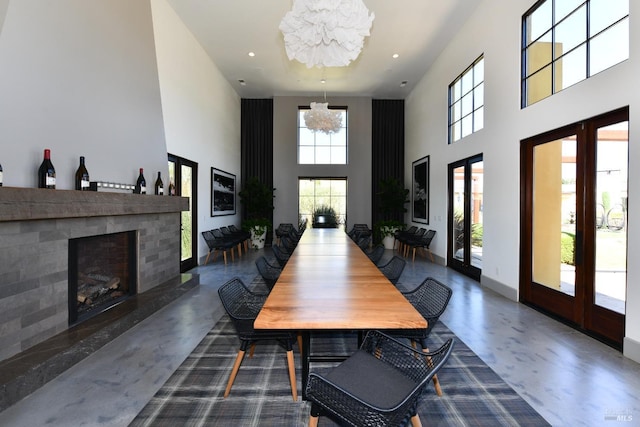 dining room with a fireplace with raised hearth, concrete flooring, recessed lighting, a notable chandelier, and baseboards