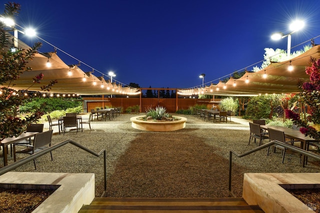 patio at night with fence, outdoor dining area, and a gazebo