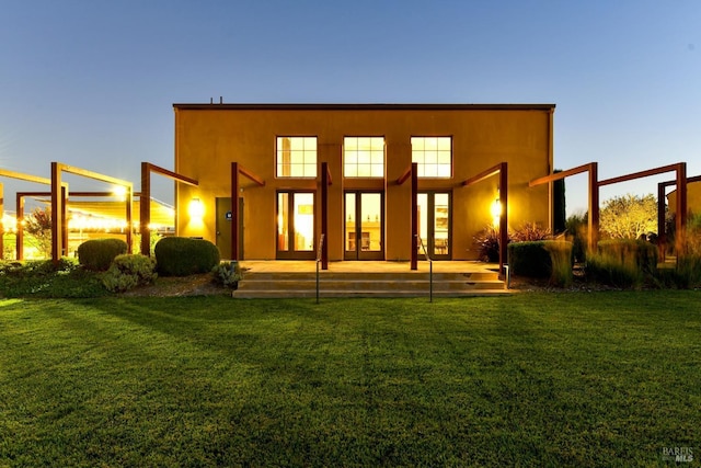 back of property with a lawn and stucco siding