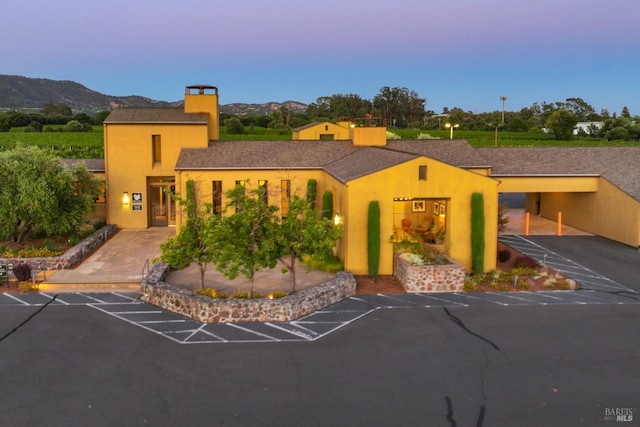 view of front facade featuring uncovered parking, a mountain view, and stucco siding