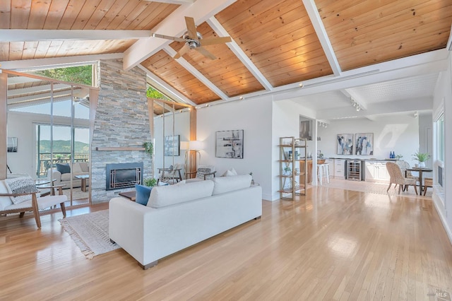 living room with high vaulted ceiling, ceiling fan, a fireplace, and light hardwood / wood-style flooring