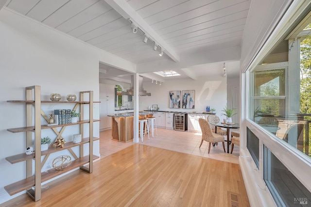 interior space featuring beamed ceiling, light hardwood / wood-style flooring, rail lighting, beverage cooler, and wood ceiling