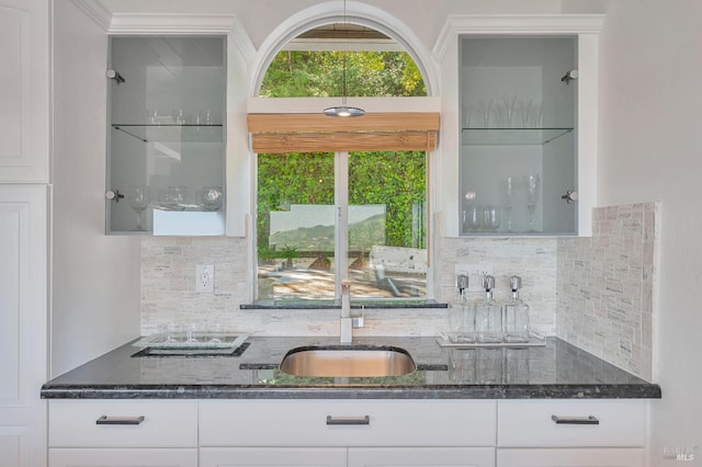 kitchen featuring dark stone counters, tasteful backsplash, sink, and white cabinets