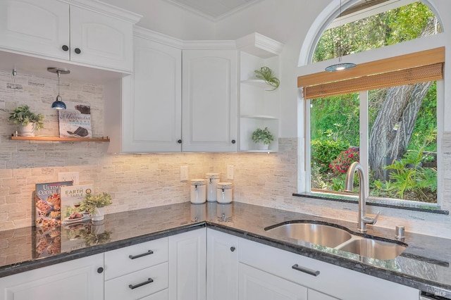 kitchen featuring crown molding, dark stone counters, sink, and white cabinets