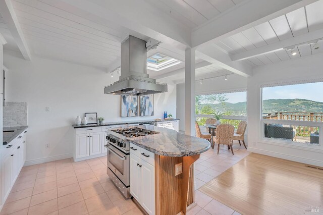 kitchen with island range hood, white cabinetry, light stone countertops, and high end stove