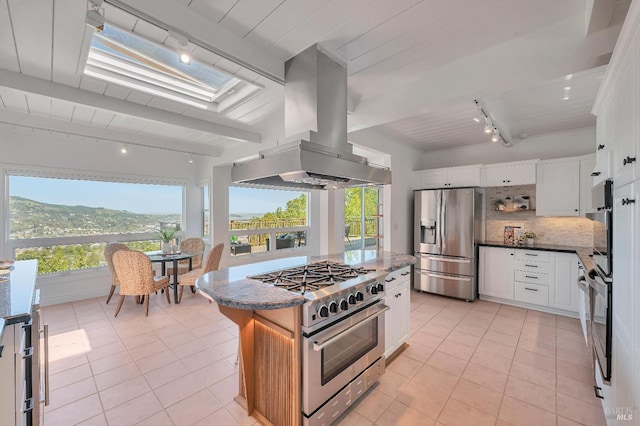 kitchen with appliances with stainless steel finishes, white cabinetry, a healthy amount of sunlight, and island exhaust hood