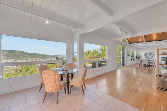 sunroom / solarium with wooden ceiling, track lighting, a mountain view, and beam ceiling