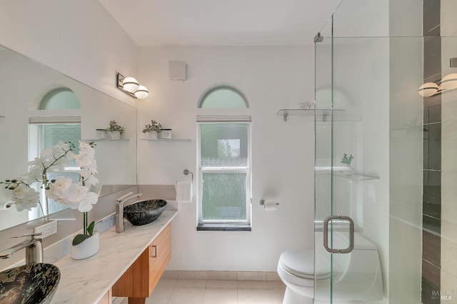 bathroom featuring a shower with door, vanity, toilet, and tile patterned floors