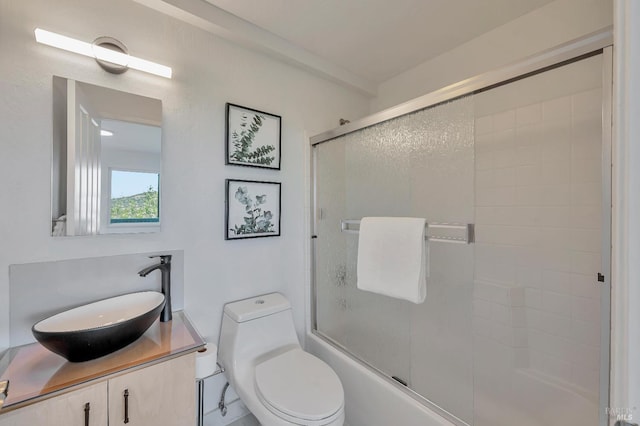 full bathroom featuring toilet, combined bath / shower with glass door, and vanity