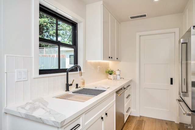 kitchen with a sink, visible vents, and white cabinets