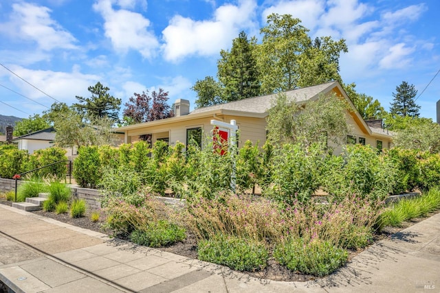 view of property hidden behind natural elements featuring a chimney