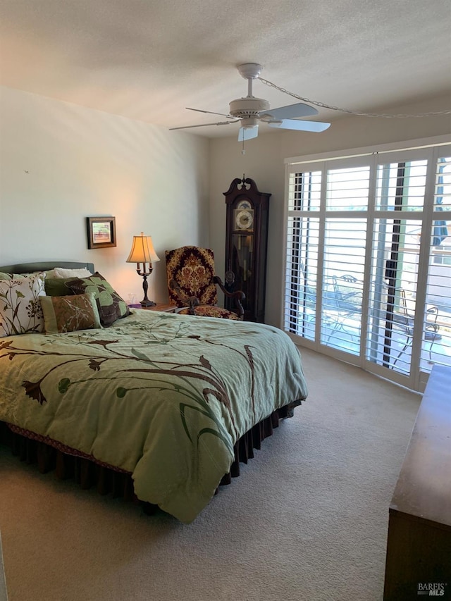 carpeted bedroom featuring access to exterior, ceiling fan, and a textured ceiling