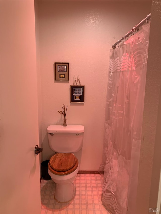 bathroom with toilet, baseboards, and tile patterned floors