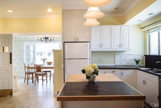 kitchen featuring ornamental molding, light tile patterned floors, sink, white refrigerator, and white cabinets