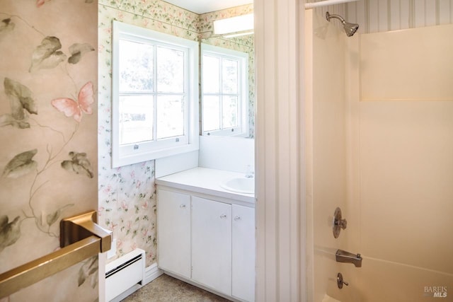 bathroom with a healthy amount of sunlight, a baseboard heating unit, washtub / shower combination, and vanity