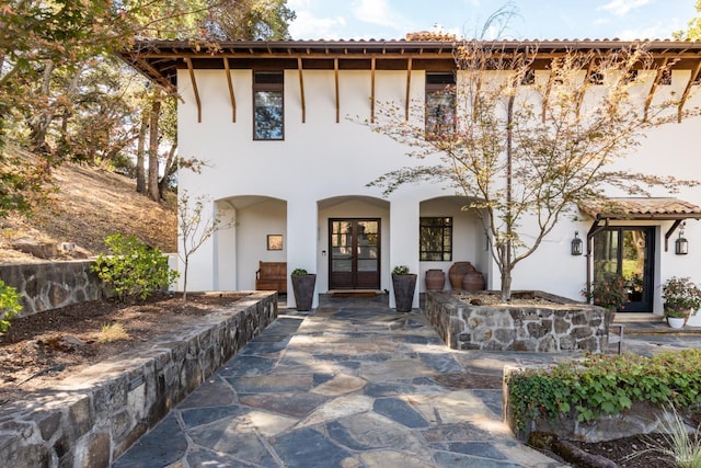 mediterranean / spanish-style home featuring a tiled roof, french doors, and stucco siding