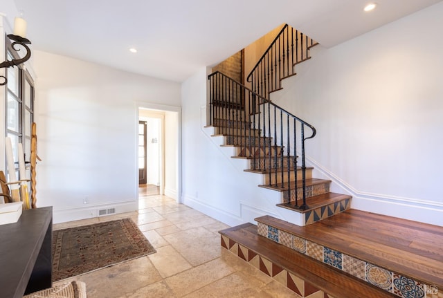 stairway featuring visible vents, baseboards, stone tile flooring, and recessed lighting