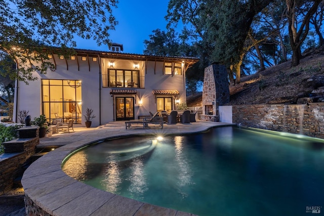 back house at twilight with a patio and a balcony