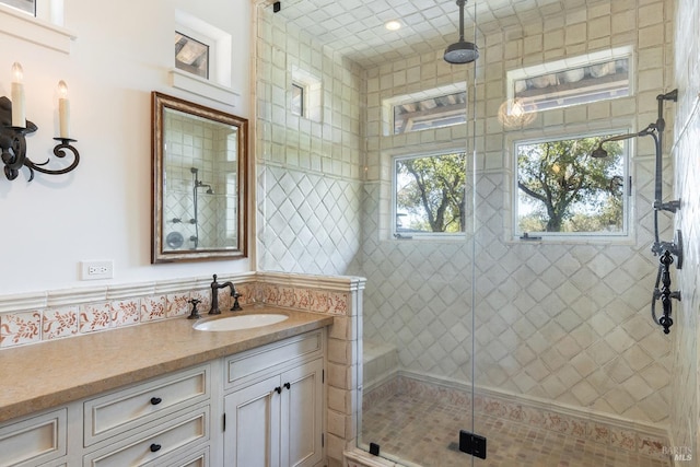 full bathroom with a shower stall, vanity, and tile walls