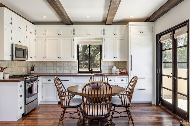 kitchen with dark wood-type flooring, stainless steel appliances, and beamed ceiling