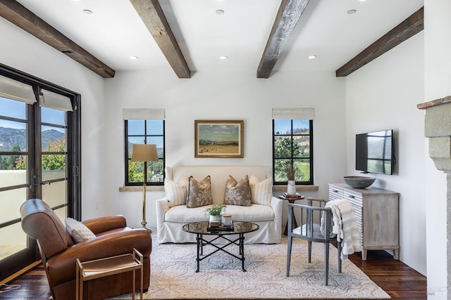 living area with wood finished floors, a healthy amount of sunlight, and beam ceiling