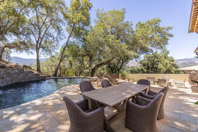 view of patio featuring a mountain view, an outdoor pool, and outdoor dining space