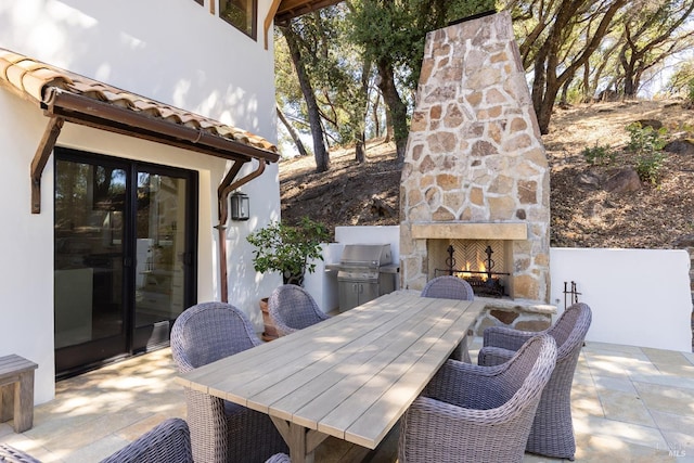 view of patio with outdoor dining area, a grill, and an outdoor stone fireplace