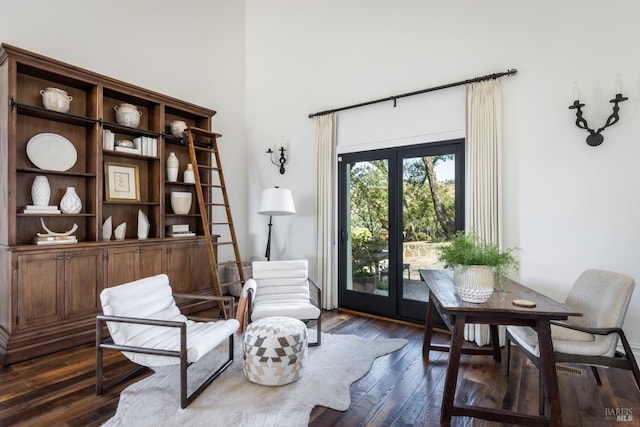 sitting room featuring french doors, a towering ceiling, and dark wood finished floors