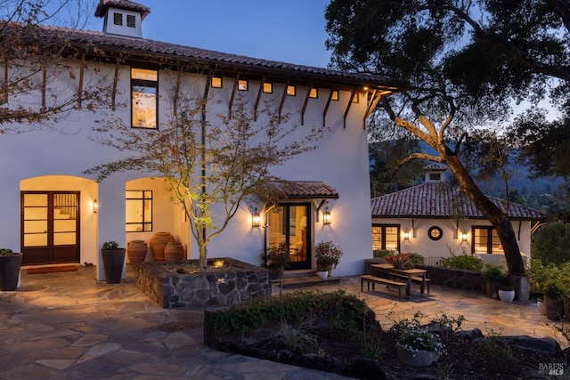 mediterranean / spanish home featuring a patio area, french doors, a tile roof, and stucco siding
