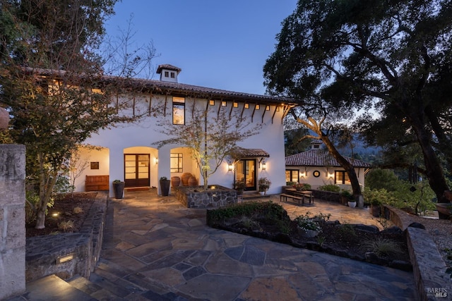 rear view of property featuring stucco siding, french doors, and a patio