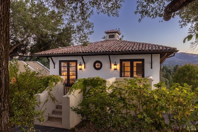 exterior space with stucco siding and a tile roof
