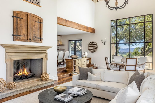 living room with a premium fireplace, a high ceiling, wood-type flooring, and beam ceiling