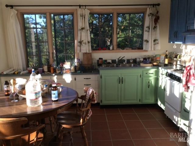 kitchen with white range with gas cooktop, dark tile patterned flooring, and sink