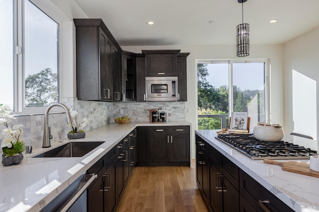 kitchen with hardwood / wood-style floors, decorative light fixtures, sink, dark brown cabinetry, and stainless steel appliances