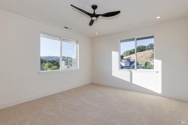 empty room featuring carpet floors, a wealth of natural light, and ceiling fan