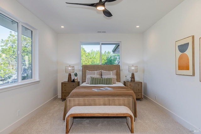 bedroom with ceiling fan, light colored carpet, and multiple windows