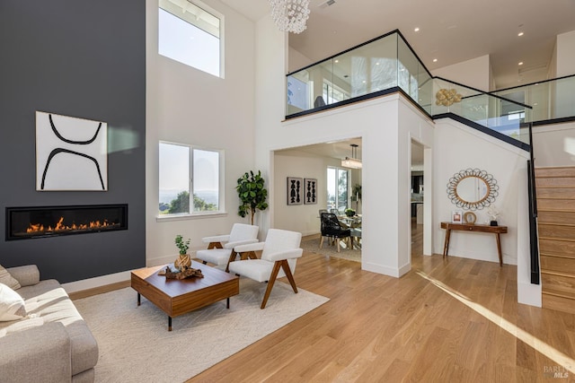 living room with an inviting chandelier, a large fireplace, and light wood-type flooring