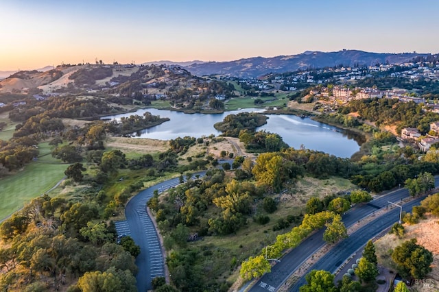 aerial view at dusk featuring a water and mountain view