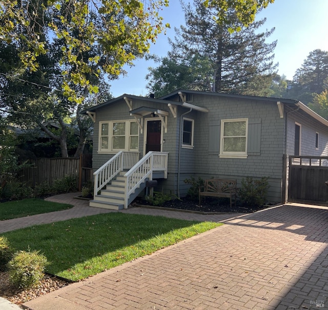 bungalow-style house with decorative driveway and fence