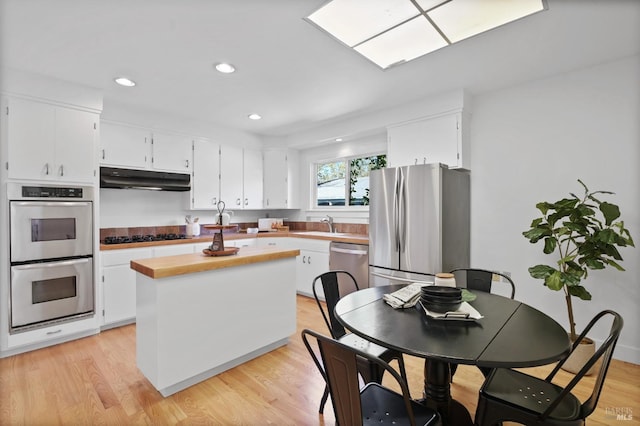 kitchen with white cabinets, under cabinet range hood, and stainless steel appliances