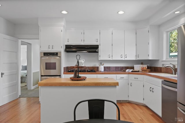 kitchen featuring white cabinetry, appliances with stainless steel finishes, under cabinet range hood, and a sink