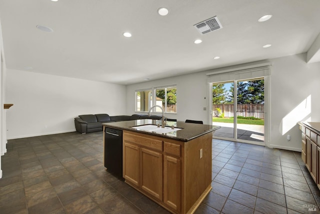 kitchen featuring black dishwasher, an island with sink, dark stone counters, and sink