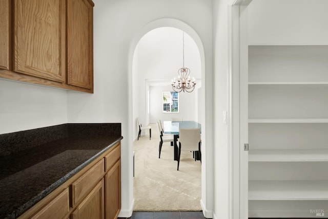 kitchen featuring carpet flooring, dark stone countertops, and an inviting chandelier