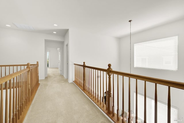 hall featuring light carpet, a healthy amount of sunlight, and an inviting chandelier