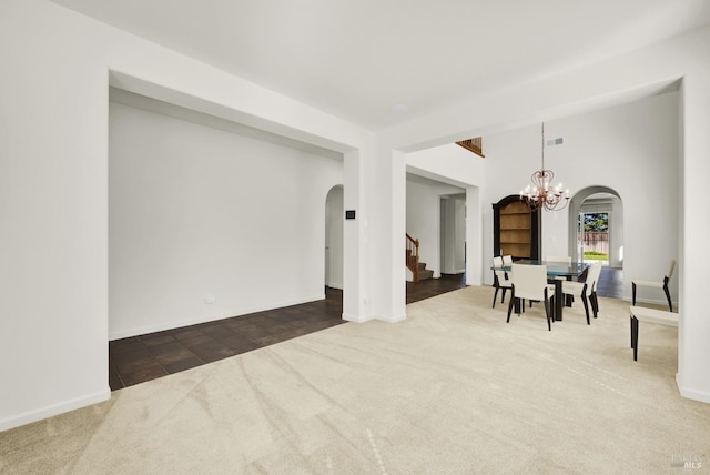 carpeted empty room featuring an inviting chandelier