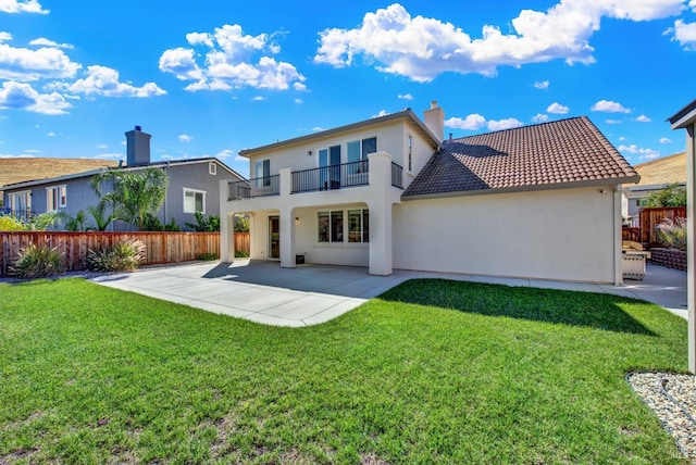 back of property with a yard, a patio, and a balcony