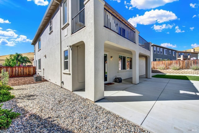 back of property featuring a balcony, central AC unit, and a patio