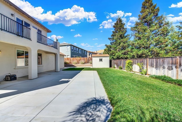 view of yard featuring a storage unit, a patio, and a balcony